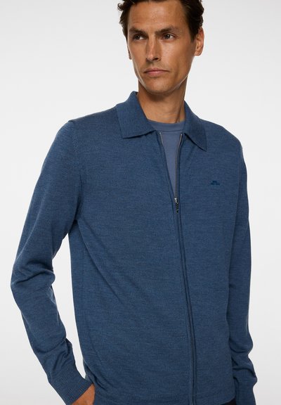 Maglione blu a zip con colletto, realizzato in un tessuto texturizzato, maniche lunghe e un piccolo logo sul petto.