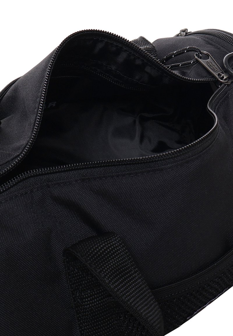 Sac de sport en tissu noir avec une fermeture éclair sur le dessus, montrant un compartiment principal vide et une poignée de transport robuste.