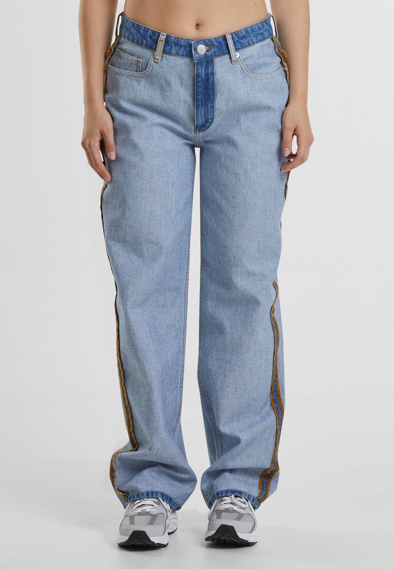 Light blue denim jeans with a relaxed fit, featuring a blue waistband, side seams with brown accents, and a traditional five-pocket design.