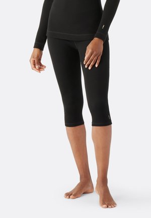 Svarta capri leggings tillverkade av elastiskt material, med en åtsittande design och kontrasterande nederkant.