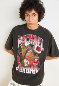 Camiseta de algodón negra con un diseño gráfico de Michael Jordan, que presenta colores brillantes, motivos deportivos y una textura desgastada.