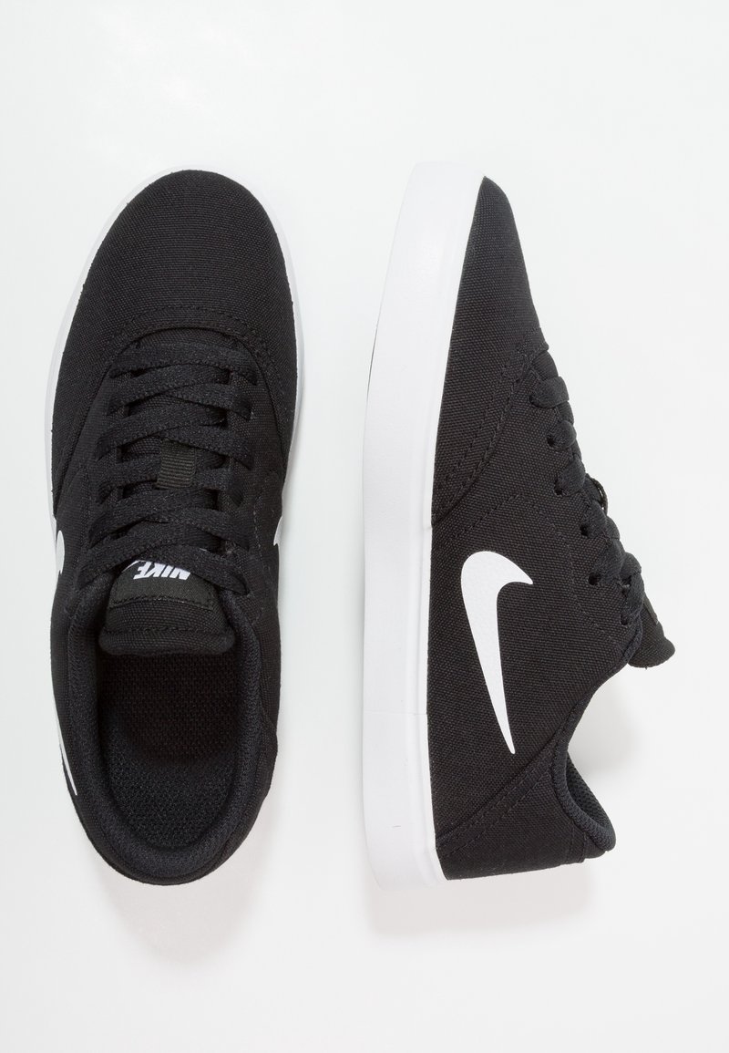 Baskets Nike noires avec logo swoosh blanc, semelles blanches et lacets noirs, vues de dessus et de côté sur un fond blanc.