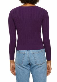 Lila ribbad långärmad tröja med en figurnära siluett och bred halsringning, kombinerad med ljusblå högmidjade jeans.