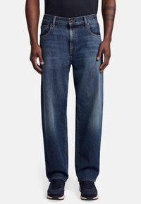 Granatowe dżinsy o luźnym kroju, pięć kieszeni i kontrastowe szwy. Prosty krój z podwiniętymi nogawkami.