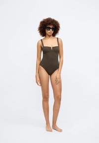 Swar svart badedrakt med firkantet utringning, brede stropper, små geometriske mønstre over hele, og en subtil nøkkelhulldetalj foran.