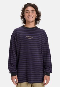 Paars en zwart gestreept long-sleeve shirt met een ronde halslijn en een relaxte pasvorm. Heeft een logo in het midden. Gemaakt van zachte stof.
