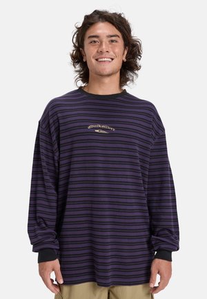 Lila und schwarz gestreiftes Langarmshirt mit Rundhalsausschnitt und lockerer Passform. In der Mitte befindet sich ein Logo. Hergestellt aus weichem Stoff.