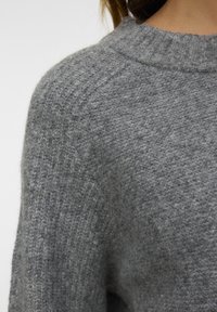 Maglione grigio lavorato a maglia con collo a girocollo a coste, caratterizzato da una superficie texturizzata e un motivo sottile. Materiale morbido e caldo con maniche raglan.