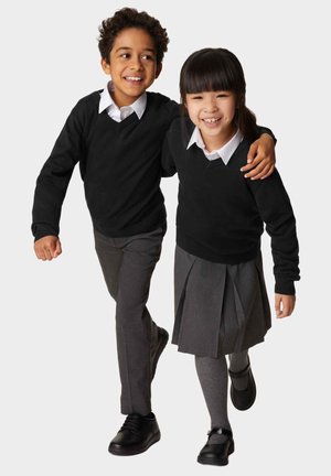 Maglioni neri a maglia sopra camicie bianche con colletto, pantaloni grigi e una gonna plissettata grigia. Bambini che camminano insieme, molto vicini. Scarpe nere.