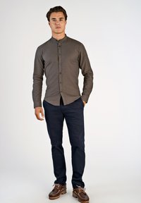 Koszula z długim rękawem w ciemnoszarym kolorze z guzikiem i kołnierzykiem, zestawiona z granatowymi spodniami i brązowymi butami na sznurówki z akcentami.