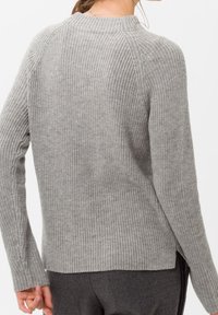 Pull gris en tricot avec une finition texturée, col rond et manches longues. Comprend des fentes latérales à l'ourlet et des poignets côtelés.