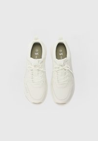 Weiße Sportschuhe aus synthetischem Material mit glatter Textur, abgerundetem Zehenbereich, Schnürdesign und dezenten Perforationen an den Seiten.