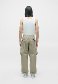 Khaki cargo bukser med elastisk talje, sidelommer og justerbare manchetter, parret med en tætsiddende hvid tanktop. Glat stoftekstur.