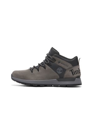 Botas de senderismo impermeables grises con un diseño de media caña, material de gamuza texturizada, acentos negros y suela de goma resistente, con la marca Timberland.