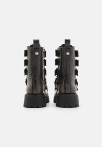 Bocanci din piele neagră, cu tălpi groase, având o finisare texturată, cu porțiuni de prindere la spate și cinci curele decorative pe fiecare parte.