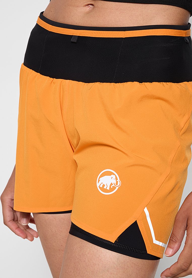 Pantalones cortos deportivos naranjas con una cintura negra, que presentan un logo blanco, aberturas laterales y una textura suave y ligera.