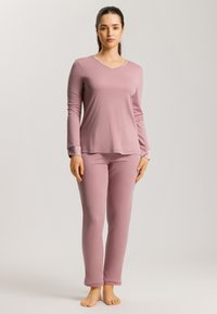 Långärmad rosa loungewear-set gjort av mjukt tyg, med en v-ringat topp och åtsittande byxor, med släta sömmar och inga synliga mönster.