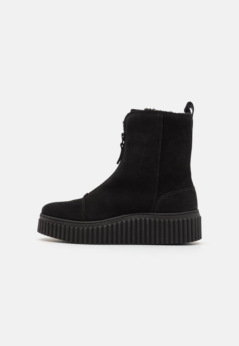 Botte mi-mollet en daim noir avec semelle plateforme épaisse à rainures, fermeture éclair intérieure, languette à l'arrière et doublure en peluche visible sur le bord supérieur.