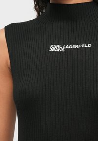 Μαύρη ριχτή αμάνικη μπλούζα με ψηλό λαιμό, με λευκό κεντημένο λογότυπο "KARL LAGERFELD JEANS" στο στήθος.