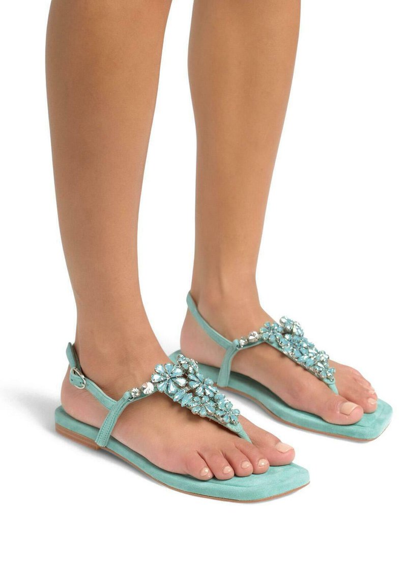Un paio di sandali blu acquamarina con un design floreale adornato di gioielli sulla cinghia, con una suola piatta e chiusura a fibbia alla caviglia.