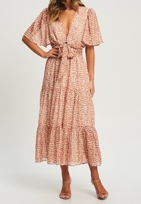 Maksimekko pehmeästä, tekstuurilla varustetusta kankaasta, jossa on vaaleanpunainen ja beige eläinkuos, lyhyet liehuvat hihat, syvä V-muoto ja solmittava vyötäröyksityiskohta.