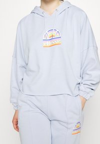 Felpa leggera blu con una vestibilità ampia, caratterizzata da una grafica arcobaleno e un logo. Tessuto morbido con cordino regolabile sul cappuccio.