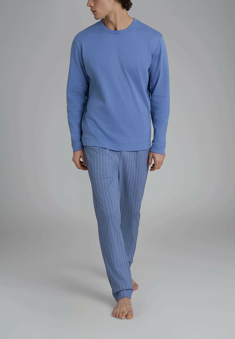 Camicia a maniche lunghe azzurro chiaro abbinata a pantaloni da pigiama a righe blu e bianche. Tessuto morbido, vestibilità rilassata e taglio dritto.