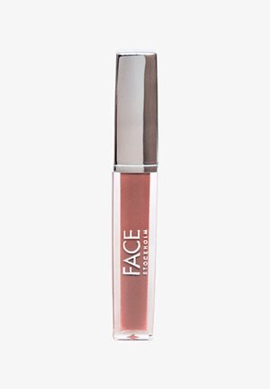 Tube de gloss à lèvres avec un bouchon argenté métallique et un corps transparent montrant une couleur rose pâle, marqué FACE Stockholm en lettres blanches.
