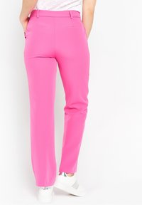 Pink straight-leg trousers with a smooth finish, featuring a wide waistband, two back pockets, and a clean hem. Paired with white sneakers.