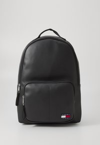 Black backpack made of smooth synthetic material, featuring a front zippered pocket, curved shape, and a logo patch on the lower right side.