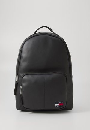 Black backpack made of smooth synthetic material, featuring a front zippered pocket, curved shape, and a logo patch on the lower right side.