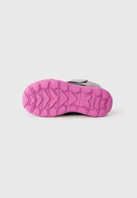 Sneakersåle med en strukturert rosa gummisåle med et sikksakk-mønster, aksentert med nedsenkede områder for bedre grep. Svart mellomsole synlig.