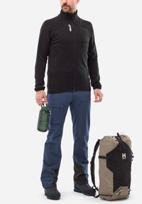 Veste en polaire noire avec poches zippées, pantalon bleu marine, bouteille d'eau verte et sac à dos beige avec des accents noirs et un logo. Matériaux texturés.