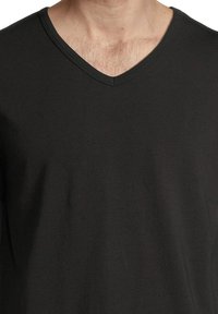 Svart t-shirt med v-ringning, gjord av mjukt tyg. Har en jämn yta med en enhetlig färg och förstärkt sömnad runt halsringningen.