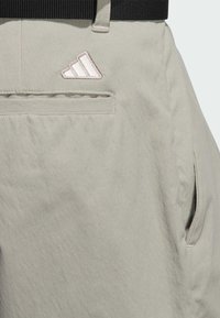 Lysegrå shorts i tekstureret stof med sort elastik i taljen, sidelommer og et broderet logo med tre striber på bagsiden.