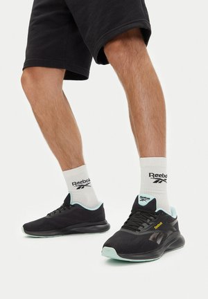 Schwarze Sportschuhe mit hellblauen Akzenten, Netzstruktur und rundem Zehenbereich. Schwarzes Logo an der Seite; getragen mit weißen Reebok-Socken.