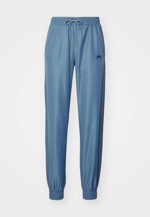 Pantaloni atletici albaștri dintr-un material neted, cu talie elastică, cordon de ajustare și manșete elastice; au buzunare laterale și un logo.