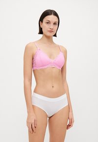 Rosa spetsbralette med justerbara axelband, med en triangelform och vågiga kanter. Matchas med vita, sömlösa hipsterunderkläder.