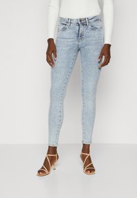 Jeans ajustados de color azul claro con un sutil patrón de puntos, que cuentan con un clásico diseño de cinco bolsillos y una cintura de altura media.