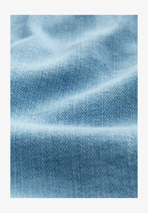 Gaiši zils denims audums ar mīkstu tekstūru, kas raksturojas ar twill auduma rakstu un nelielām krokiņām, izceļot tā elastīgo krišanu.