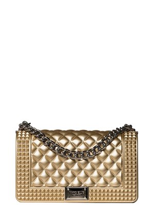 Gouden gequiltte handtas met een kettinghengsel, studaccenten, rechthoekige vorm en een metalen logo plaat aan de voorkant.