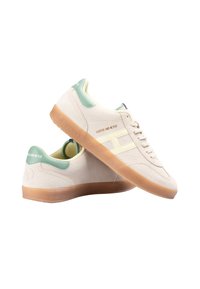 Beige ruskinds sneakers med grønne accenter, der har en gummi sål i naturfarve, præget logo og teksturerede detaljer på siderne og hælen.