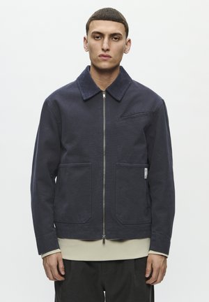 Dunkelblaues Zip-Up-Jackett aus Baumwolle mit einem Cordkragen, zwei Vorderaschen, einer Brusttasche und einer leicht taillierten Passform.