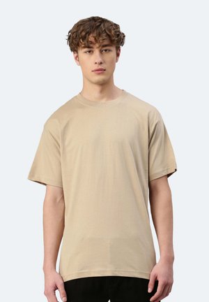 T-shirt beige a maniche corte con colletto rotondo. Tessuto morbido e liscio con una vestibilità rilassata. Design minimalista, senza loghi o motivi visibili.