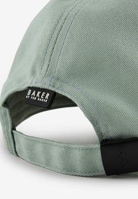 Roheline müts, millel on tekstureeritud kangas, must silt, millel on kiri "BAKER by TED BAKER" ja must reguleeritav rihm.