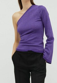 Haut violet à une épaule en matière texturée et scintillante. Le design présente une coupe asymétrique avec une manche longue et un ourlet côtelé.