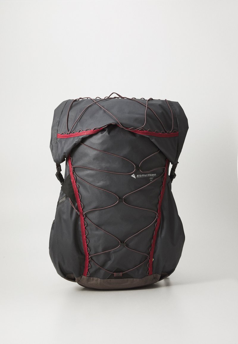 Black backpack made of durable fabric, featuring red accent lines and a bungee cord design, with adjustable straps and a structured shape.