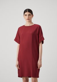 Burgundy klänning i lätt material, med en enkel rund halsringning och korta ärmar med subtil textur samt en avslappnad passform.
