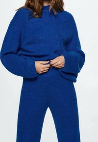 Blauwe gebreide trui met een textuurfinish, voorzien van brede mouwen en een ontspannen pasvorm. Gecombineerd met bijpassende blauwe gebreide broek.