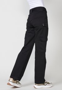 Pantalones cargo negros con un corte recto, múltiples bolsillos y detalles en metal plateado. Fabricados con un tejido duradero y una textura suave.